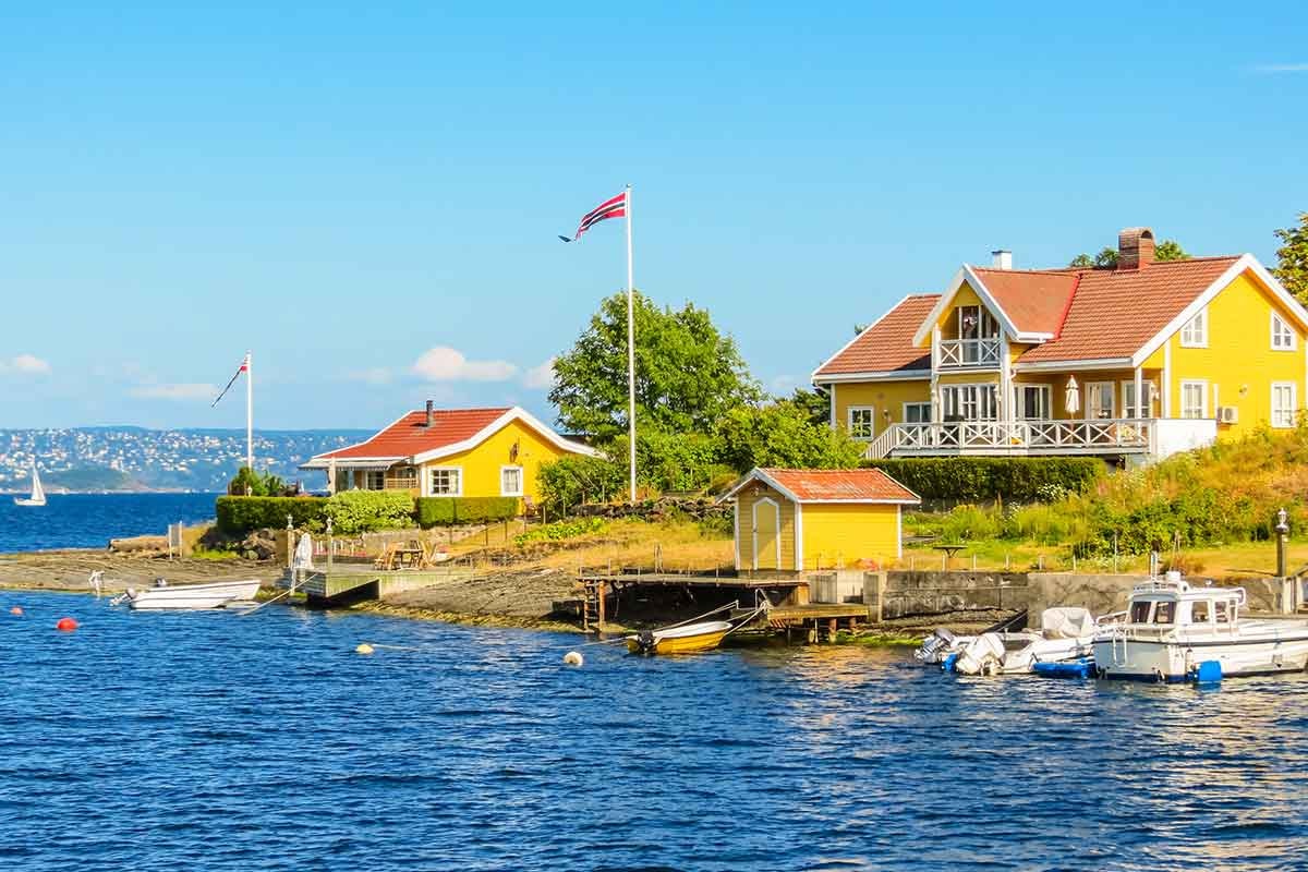 Fritidsbolig ved sjøen i Norge med båter og båthus, til illustrasjon for kjøpe hytte
