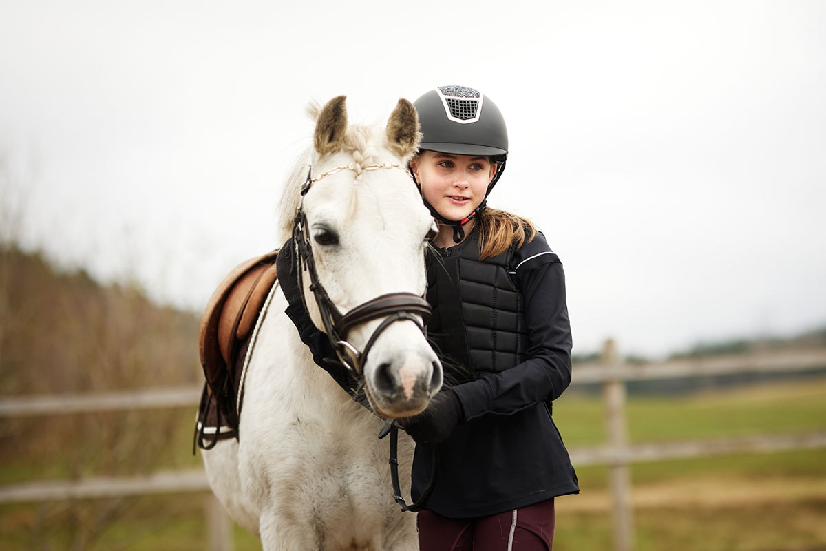 Barn sitter i fanget til mor og holder en sparegris, til illustrasjon for spare til barna