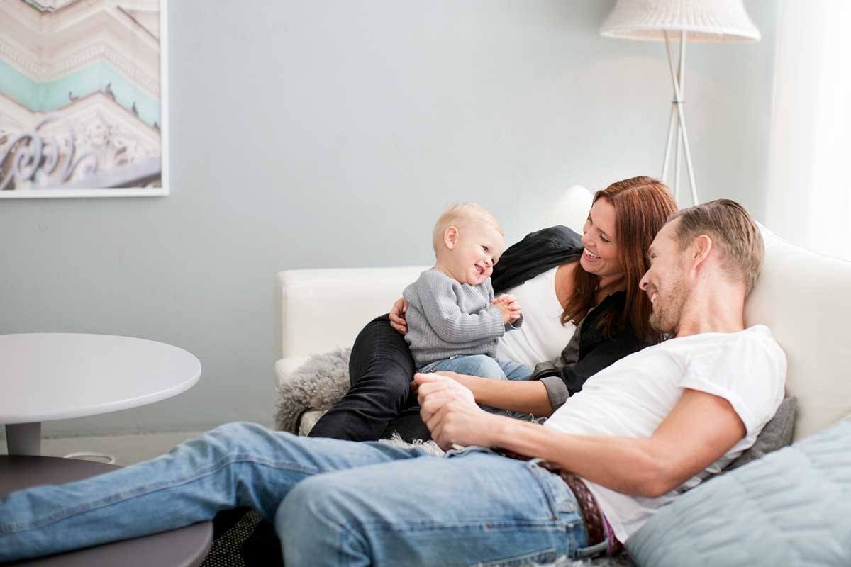 Foreldre med liten gutt på fanget, til illustrasjon for hvor mye koster det å ha barn