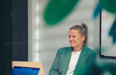 En kvinne sitter ved et skrivebord med laptop og planlegger sitt neste steg i prosessen med å bytte bank
