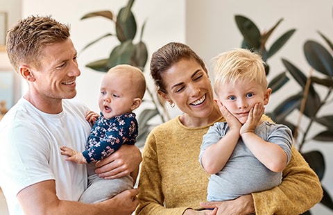 Far, baby, mor og sønn står i stua og smiler, til illustrasjon for renteendring