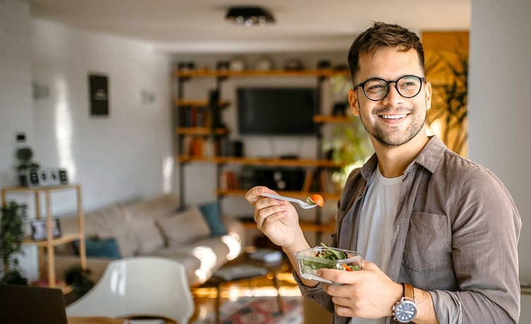 Mann er hjemme og og spiser en salat, illustrasjon til lønnskonto