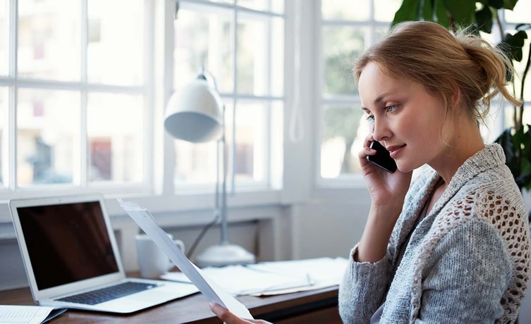 Kvinne snakker i telefonen mens hun holder et dokument, til illustrasjon for gjeldsordning