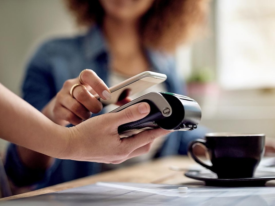 Dame bruker Samsung Pay til å betale for en kopp kaffe