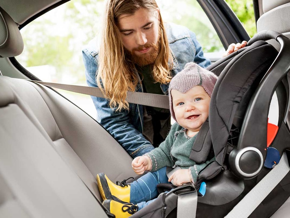 Mann sjekker bilstolen til en baby, til illustrasjon for billån