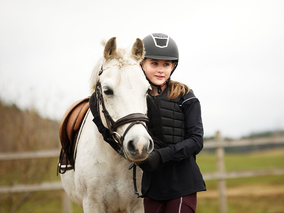 Barn sitter i fanget til mor og holder en sparegris, til illustrasjon for spare til barna