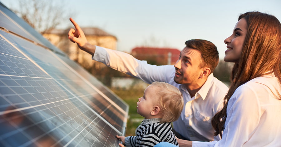 Mann peker på solcelleanlegg sammen med et barn og en kvinne, til illustrasjon for kjøpe solcelleanlegg