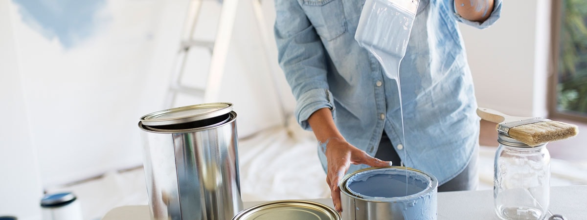 Dame dupper malingskost i malingsspann, til illustrasjon for pusse opp før salg av bolig