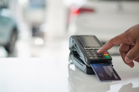 Mann bruker bankterminal til å sette inn penger i butikk
