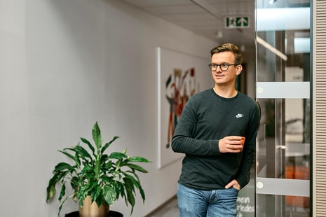 BN Bank ansatt Mathias lener seg mot glassvegg og holder en kaffekopp, til illustrasjon for AS eller ENK