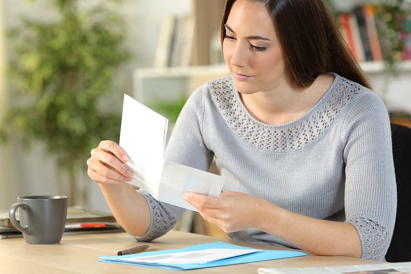 Dame sitter ved kontorpult og holder på en brevgiro