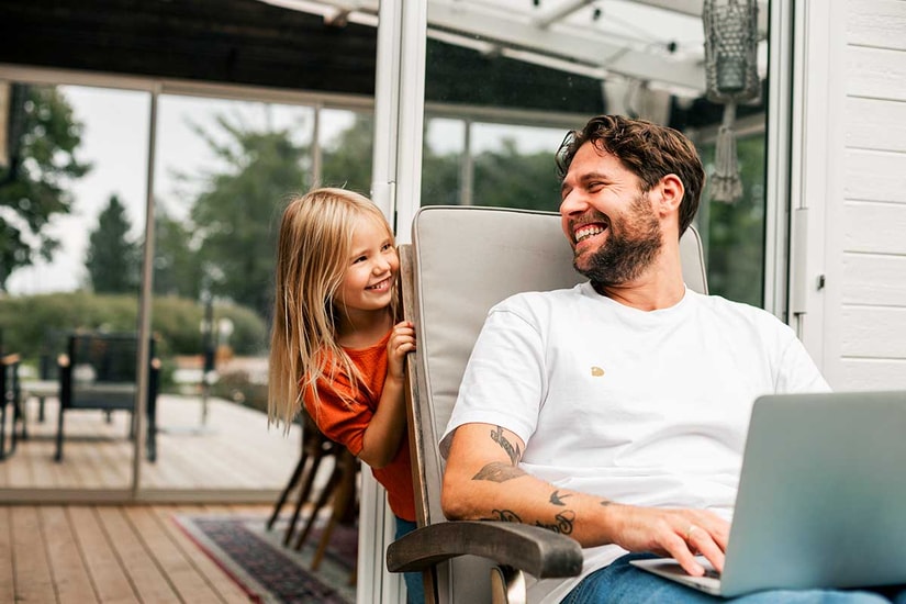 Barn og mann smiler ute på terassen med PC fremfor seg, til illustrasjon for bufferkonto