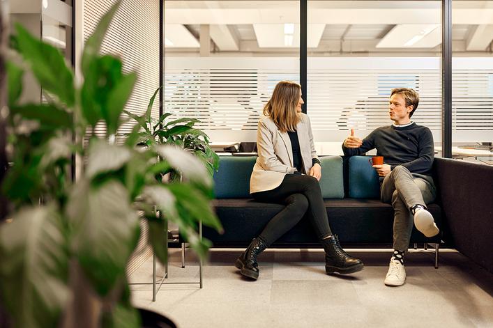 To personer sitter på en sofa i et kontor og diskuterer hva fastrenteinnskudd er