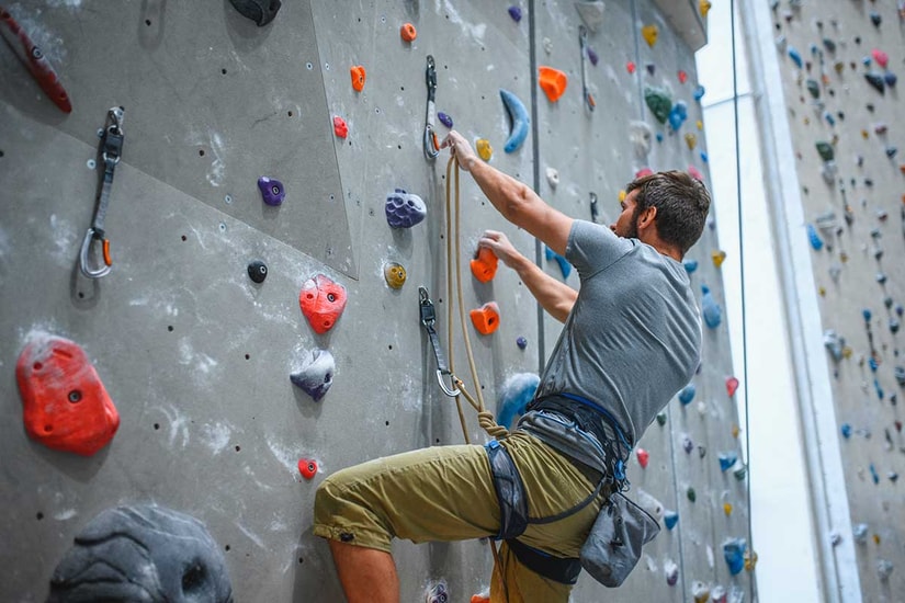 Mann klatrer i klatrevegg, til illustrasjon for bedriftskunder som er i lag og forening