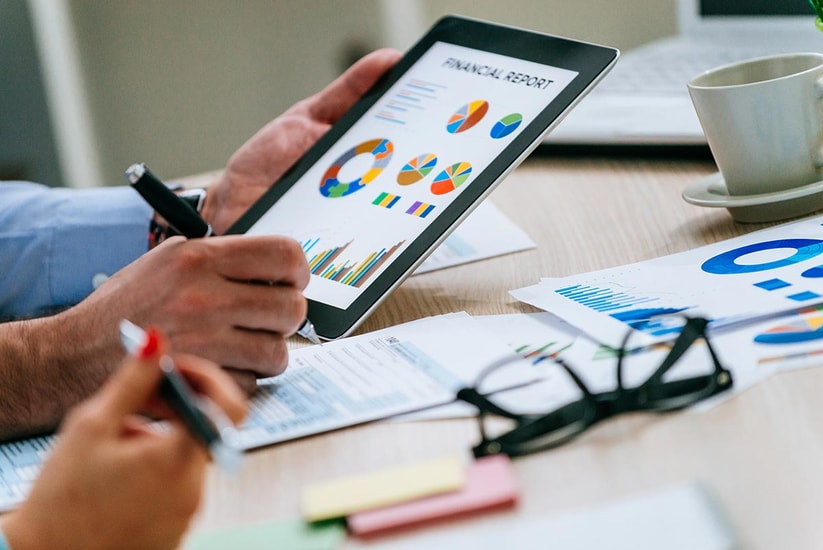 To personer jobber på et nettbrett som viser finansiell informasjon