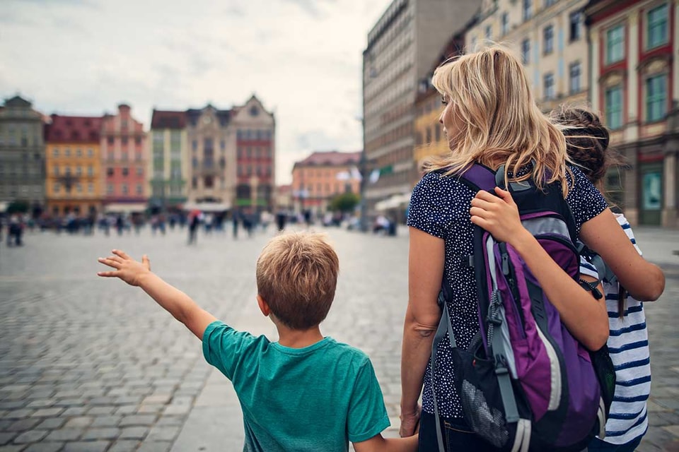 En kvinne og to barn går sammen i sentrum av en by, til illustrasjon for kort