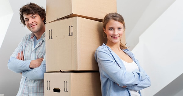 Ungt par lener seg på flere flytteesker, til illustrasjon for selge bolig