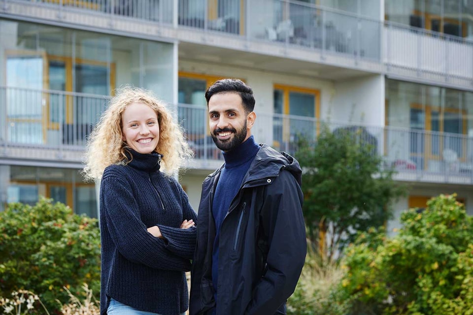 Dame og mann fremfor boligblokk, til illustrasjon for dokumentavgift ved kjøp av bolig