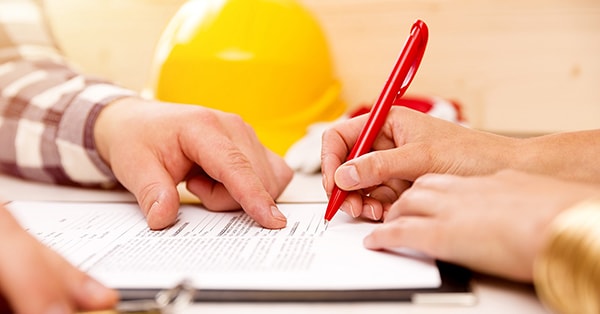 Mann og kvinne ser over tilstandsrapporten og signerer med rød penn