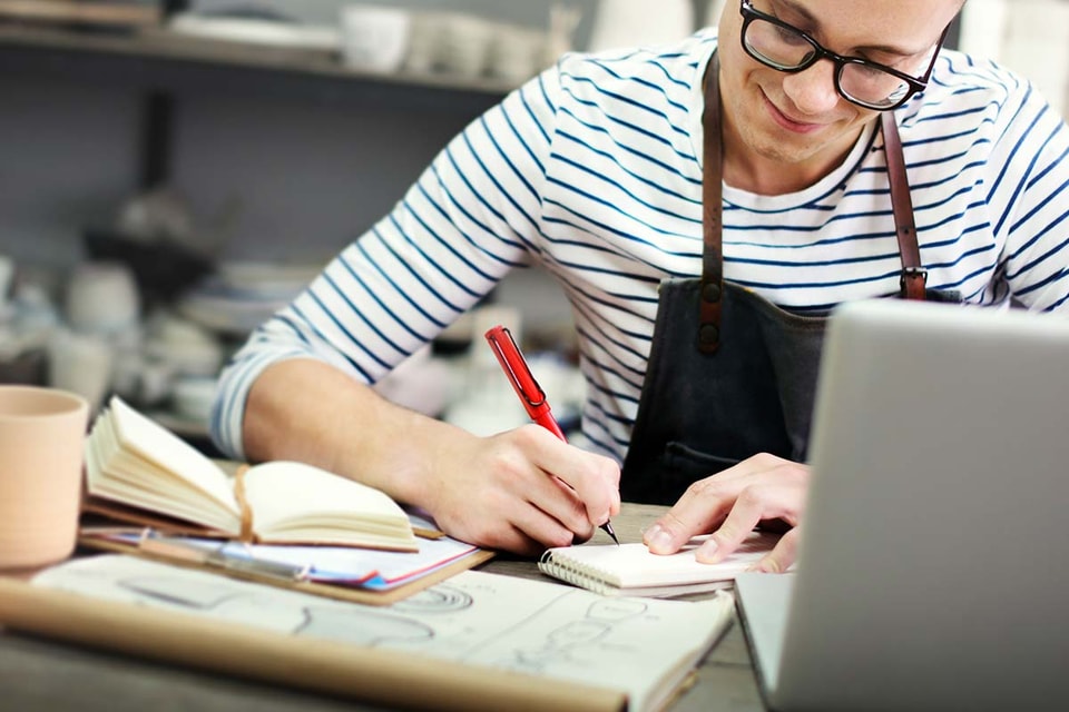 En mann med briller jobber på en laptop, fokusert på arbeid relatert til skattetrekkskonto