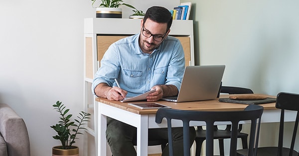 Mann sitter ved kjøkkenbordet og sjekker skattemeldingen