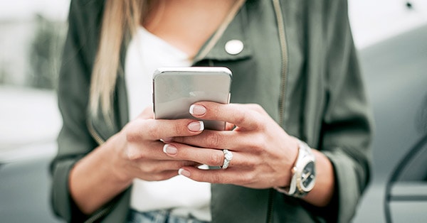 Dame som skriver på mobil, til illustrasjon for svindel på e-post og sms