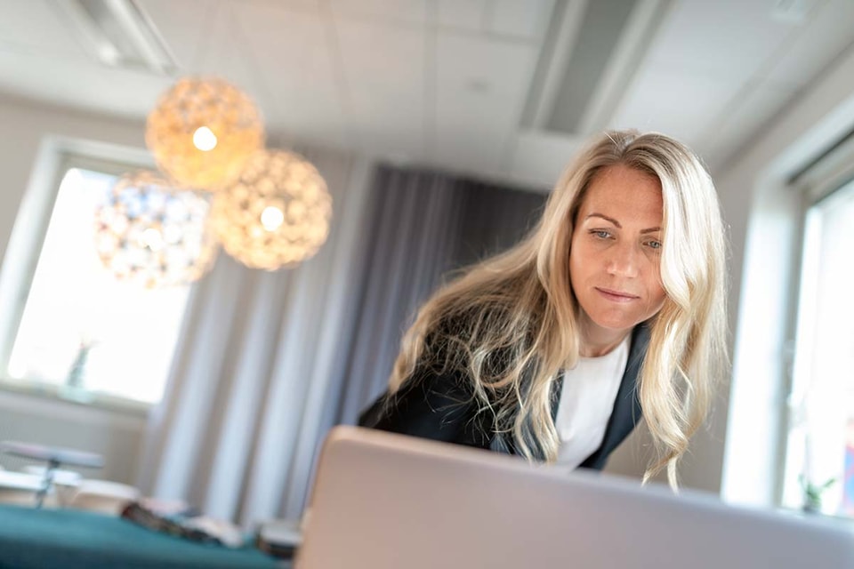 Kvinne med blazer lener seg over en datamaskin, til illustrasjon for finansavtaleloven