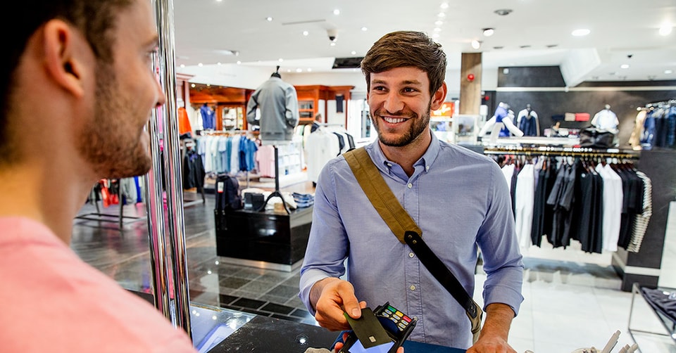 Mann handler med kredittkort på klesbutikk