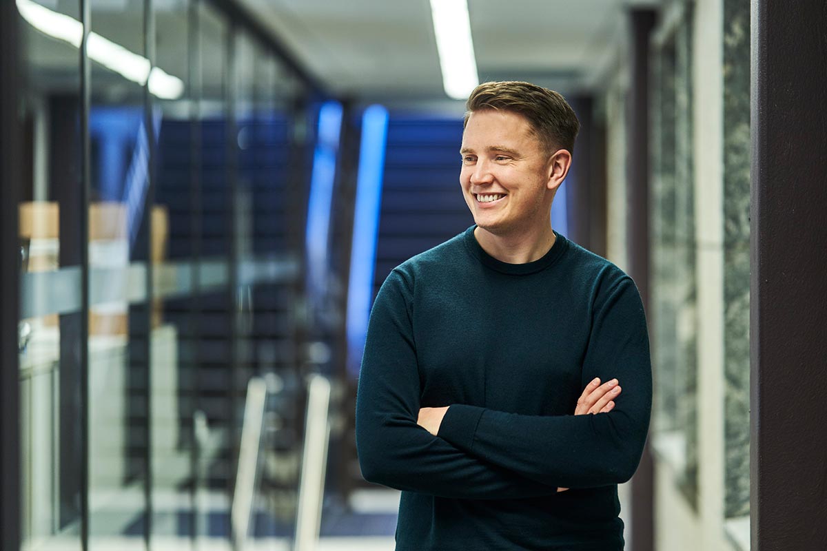 En mann med armene krysset står i en kontorgang, vurderer fordelene ved høyrentekontoer