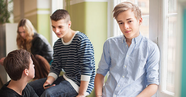 Gutt smiler med andre medelever bak seg, til illustrasjon for barne og ungdomsprodukter